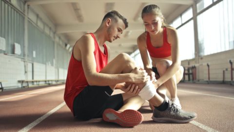 woman helping sportsman with injury during cardio training