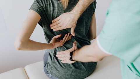 crop unrecognizable woman showing chiropractor painful spot on back