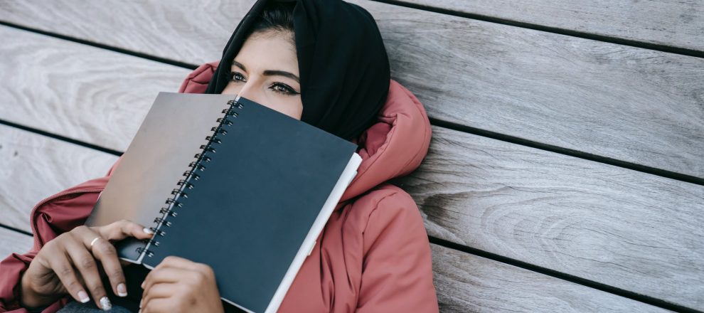 tired student resting on terrace covering face with notepad